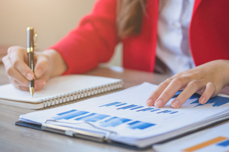 Marketing, Financial, Accounting, Planning, business women analyze company results and profits with graph statistics. Use a laptop computer and a calculator to calculate the company is balance.の写真素材