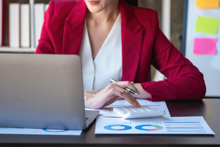 Marketing, Finance, Accounting, Planning, Portrait of a female accountant using a calculator and laptop to calculate balance using graphs for customers.の写真素材