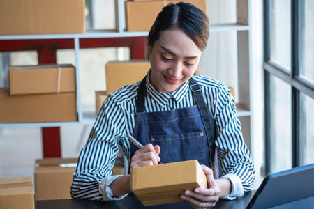 Asian female entrepreneur starting an online sales business using laptops, tablets, and smartphones to place orders and check products inside her own office, SME online concept.の写真素材