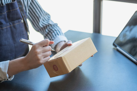 Asian female entrepreneur starting an online sales business using laptops, tablets, and smartphones to place orders and check products inside her own office, SME online concept.の写真素材