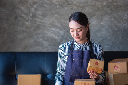Asian female entrepreneur starting an online sales business using laptops, tablets, and smartphones to place orders and check products inside her own office, SME online concept.の写真素材