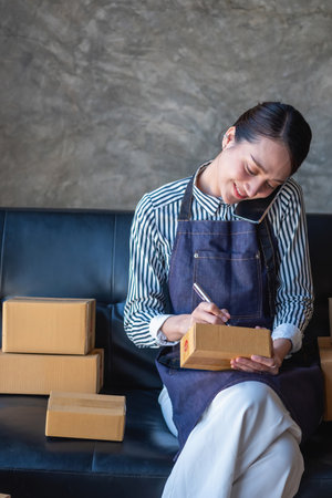 Asian female entrepreneur starting an online sales business using laptops, tablets, and smartphones to place orders and check products inside her own office, SME online concept.の写真素材