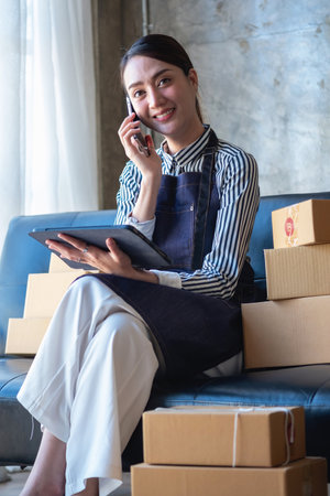 Asian female entrepreneur starting an online sales business using laptops, tablets, and smartphones to place orders and check products inside her own office, SME online concept.の写真素材