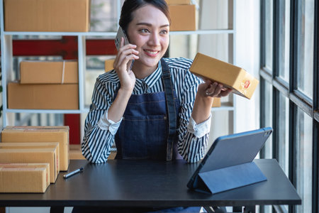 Asian female entrepreneur starting an online sales business using laptops, tablets, and smartphones to place orders and check products inside her own office, SME online concept.の写真素材