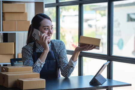 Asian female entrepreneur starting an online sales business using laptops, tablets, and smartphones to place orders and check products inside her own office, SME online concept.の写真素材