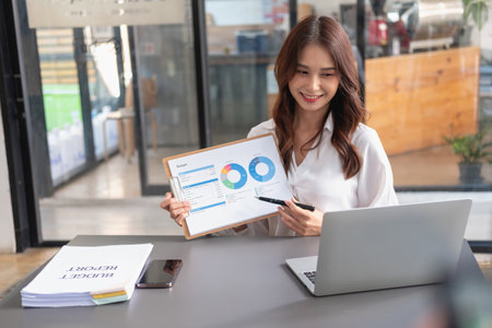 Marketing, Financial, Accounting, Planning, business women analyze company results and profits with graph statistics. Use a laptop computer and a calculator to calculate the company is balance.の写真素材