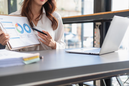 Marketing, Financial, Accounting, Planning, business women analyze company results and profits with graph statistics. Use a laptop computer and a calculator to calculate the company is balance.の写真素材