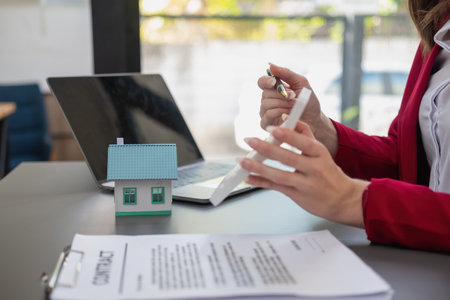 Accountant, businessman, real estate agent, Businessman handing model house to customers along with house interest calculation documents for customers to sign.の写真素材