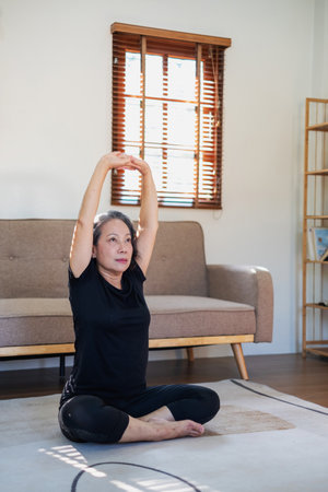 Asian elderly woman meditating practicing yoga for good health At an older age, it's about taking care of your body's health at home on a relaxing day. good health conceptの写真素材