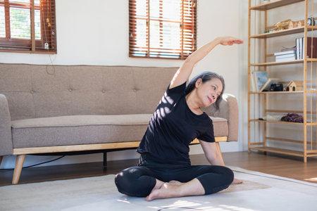 Asian elderly woman meditating practicing yoga for good health At an older age, it's about taking care of your body's health at home on a relaxing day. good health conceptの写真素材