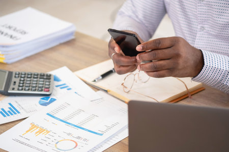 African black businessmen sit on mobile phones communicating with clients and making financial...