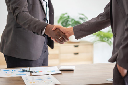 Satisfied black client shaking hands, thanking the manager for good financial deal African American businessmen shaking hands after successful business negotiations. Hiring. Buying services.の写真素材