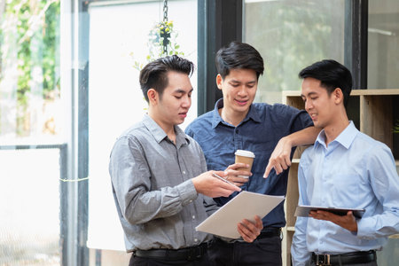 Asian business team consists of marketing staff. accountant and financial officer Help each other analyze company profits using tablets. calculator Laptop computers, graph paper, and corporate pens.の写真素材