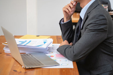 Asian business team consists of marketing staff. accountant and financial officer Help each other analyze company profits using tablets. calculator Laptop computers, graph paper, and corporate pens.の写真素材