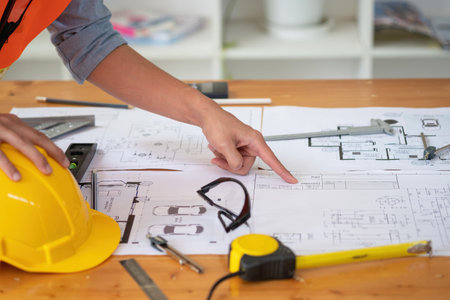 Asian engineers brainstorm and measure to document cost estimates and write floor plans for...