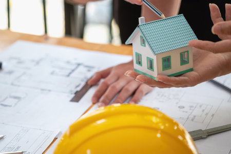Asian engineers brainstorm and measure to document cost estimates and write floor plans for...