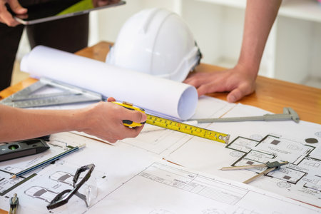Asian engineers brainstorm and measure to document cost estimates and write floor plans for...