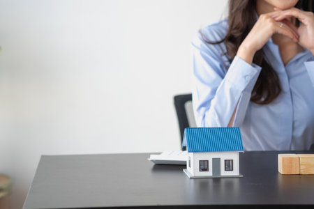 Woman saving money to buy her own house Happy holding roof over small pink piggy bank lying on the table in the living room. Close up. Finance, buying property, getting mortgage loの写真素材