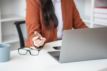 businesswoman working in the office Using calculator to calculate financial reports. Sales data with laptop computer and business documents on office table. Close up. Business finance and investment.の写真素材