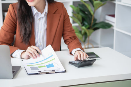 businesswoman working in the office Using calculator to calculate financial reports. Sales data with...