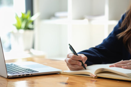 Happy young Latin female college student studying online remotely Distance university webinars Or video call on your laptop and use your computer for a virtual meeting seminar at home or on campus.の写真素材