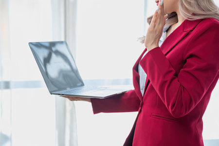 Portrait of a woman business owner showing a happy smiling face as he has successfully invested in her business using computers and financial budget documents at work.の写真素材