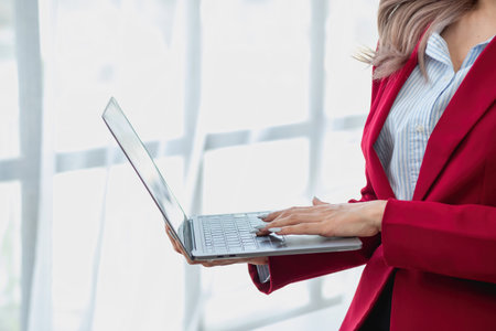 Portrait of a woman business owner showing a happy smiling face as he has successfully invested in her business using computers and financial budget documents at work.の写真素材