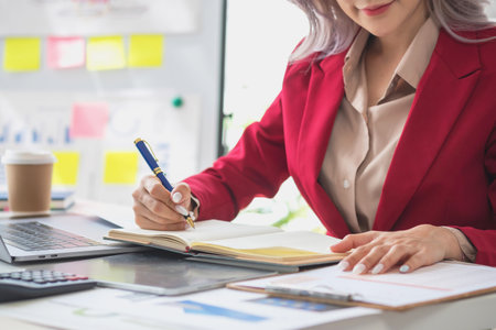 Beautiful young teen asian businesswoman using note pad thinking with planning working on financial document, tax, exchange, accounting and Financial advisor.の写真素材