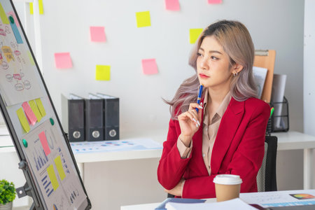 Asian businesswoman presenting a profitable company marketing plan with confidence at the office and future investment plans of the company with charts and graphs on the board.の写真素材