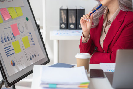 Asian businesswoman presenting a profitable company marketing plan with confidence at the office and future investment plans of the company with charts and graphs on the board.の写真素材