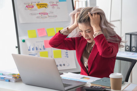 Concept Burnout Syndrome. Asian business Woman feels uncomfortable working. Which is caused by stress, accumulated from unsuccessful work And less resting body. Consult a specialist psychiatrist.の写真素材