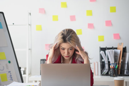 Concept Burnout Syndrome. Asian business Woman feels uncomfortable working. Which is caused by stress, accumulated from unsuccessful work And less resting body. Consult a specialist psychiatrist.の写真素材