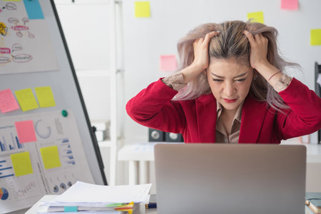 Concept Burnout Syndrome. Asian business Woman feels uncomfortable working. Which is caused by stress, accumulated from unsuccessful work And less resting body. Consult a specialist psychiatrist.の写真素材