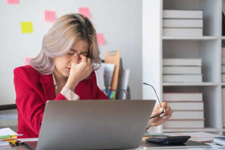 Concept Burnout Syndrome. Asian business Woman feels uncomfortable working. Which is caused by stress, accumulated from unsuccessful work And less resting body. Consult a specialist psychiatrist.の写真素材