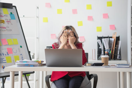 Concept Burnout Syndrome. Asian business Woman feels uncomfortable working. Which is caused by stress, accumulated from unsuccessful work And less resting body. Consult a specialist psychiatrist.の写真素材