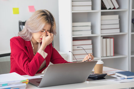 Concept Burnout Syndrome. Asian business Woman feels uncomfortable working. Which is caused by stress, accumulated from unsuccessful work And less resting body. Consult a specialist psychiatrist.の写真素材