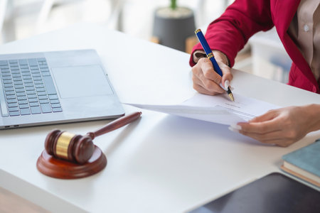 Asian female lawyer or legal advisor signing a contract The contract documents that work on your desk in the law office are there to guide you.の写真素材