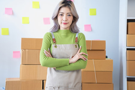 Small business entrepreneur SME, smile asian young woman, girl owner standing confident with arms crossed prepare order send to customer packing box to delivery, working online at home, ecommerce.の写真素材