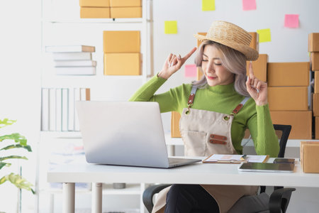 A cute Asian female blogger reviews products and camcorders on a home network, sells online, and presents fashion hats on social media. E-commerce business live stream vlogs new normal concept.の写真素材