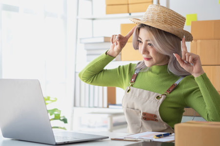 A cute Asian female blogger reviews products and camcorders on a home network, sells online, and presents fashion hats on social media. E-commerce business live stream vlogs new normal concept.の写真素材