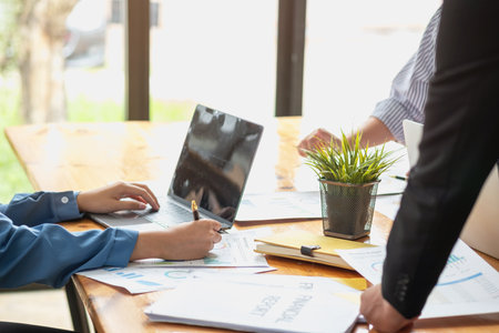 Asian business team consists of marketing staff. accountant and financial officer Help each other analyze company profits using tablets. calculator Laptop computers, graph paper, and corporate pens.の写真素材