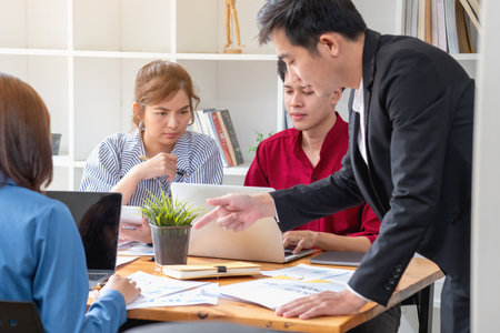 Asian business team consists of marketing staff. accountant and financial officer Help each other analyze company profits using tablets. calculator Laptop computers, graph paper, and corporate pens.の写真素材