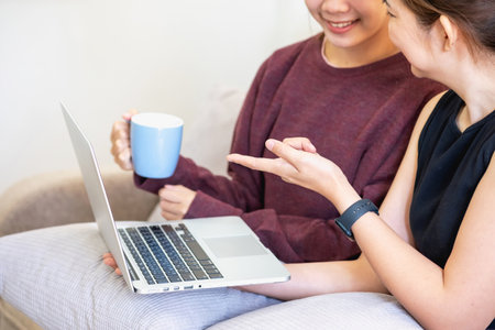Relaxed young Asian woman enjoying relaxation on a comfy sofa at home. The beautiful girl calmly relaxes and breathes fresh air in the house. Watch movies and social networks.の写真素材