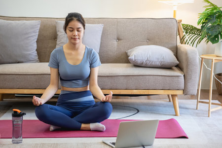 Healthy young woman doing breathing exercises at home, beautiful woman meditating at home with eyes closed, practicing yoga, doing pranayama techniques Mindfulness meditation conceptの写真素材