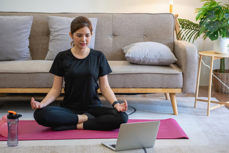 Healthy young woman doing breathing exercises at home, beautiful woman meditating at home with eyes closed, practicing yoga, doing pranayama techniques Mindfulness meditation conceptの写真素材