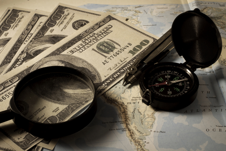 Compass with magnifier and money on map,business concept.