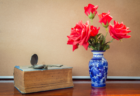 Still life artificial rose in vase with watch and book.の写真素材
