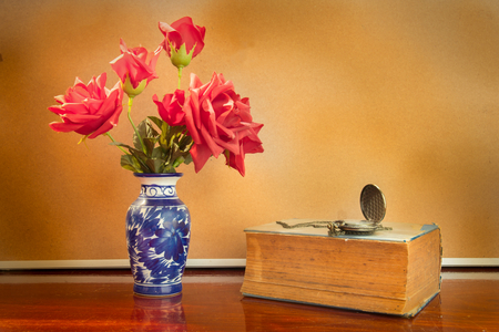 Still life artificial rose in vase with watch and book.の写真素材