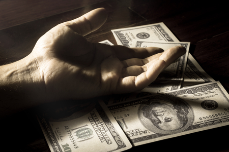 Black and white filtered human hand on dollar bills.の写真素材