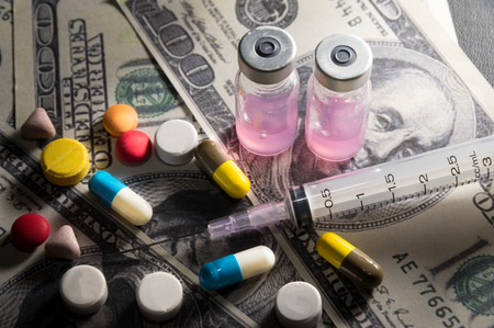 Syringe with ampule and medicine pills on money,medical concept.の写真素材